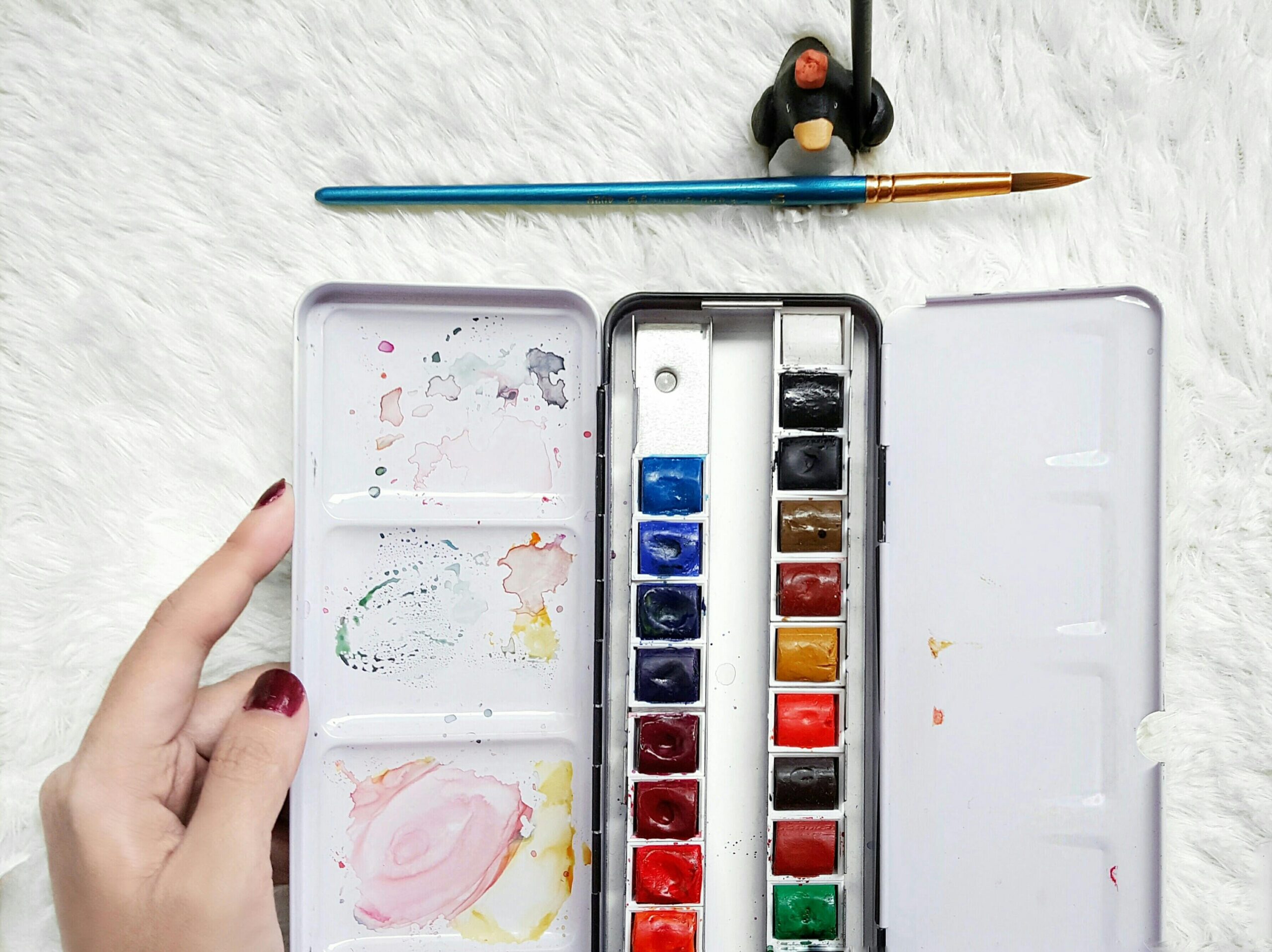 Flat lay of a watercolor palette and paintbrush, vibrant colors on display.
